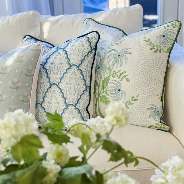 Decorative pillows on a beige sofa with white flowers in the foreground