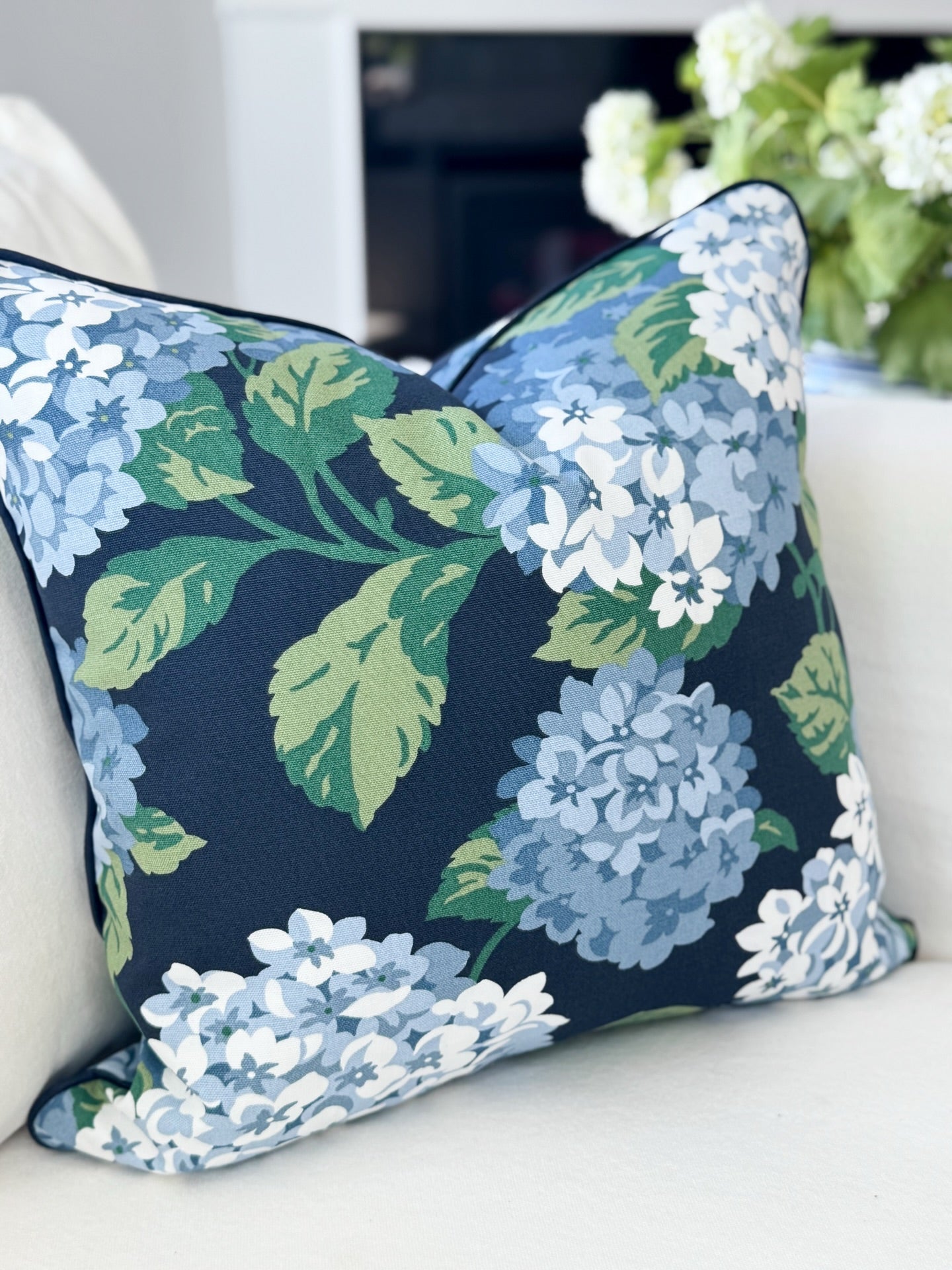 Floral-patterned pillow on a white couch with a blurred background