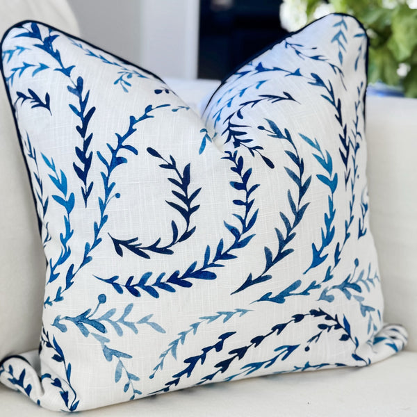 Decorative pillow with blue leaf pattern on a white couch