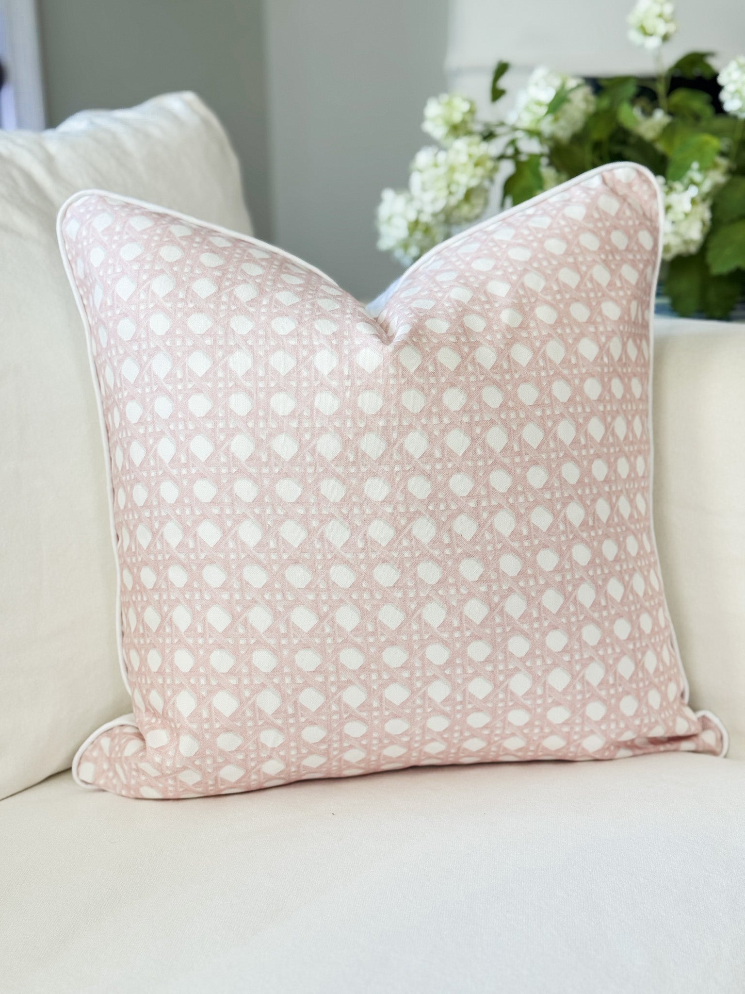Pink patterned pillow on a beige sofa with a blurred background