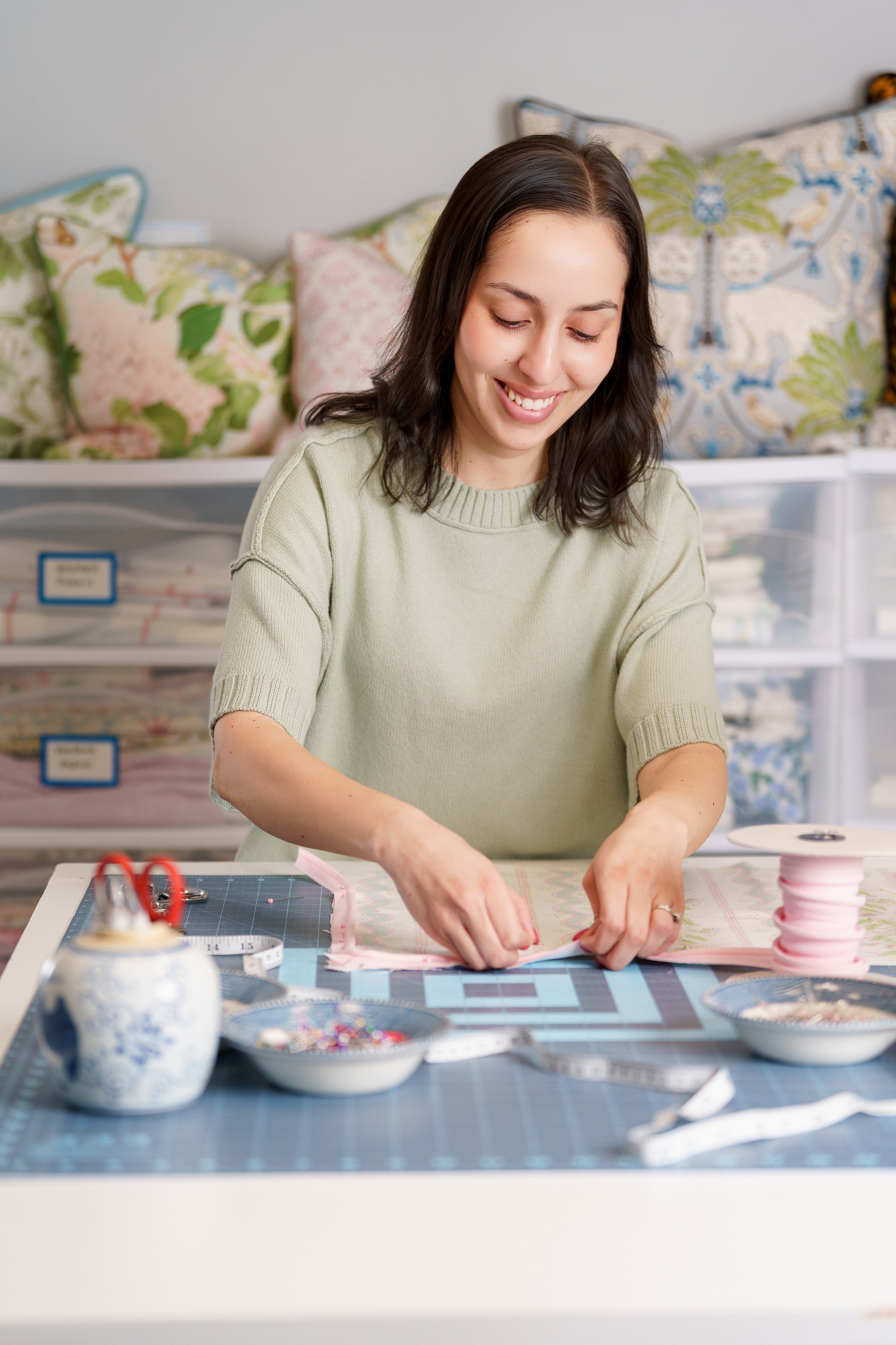 Woman working at a craft table with various supplies in a home setting