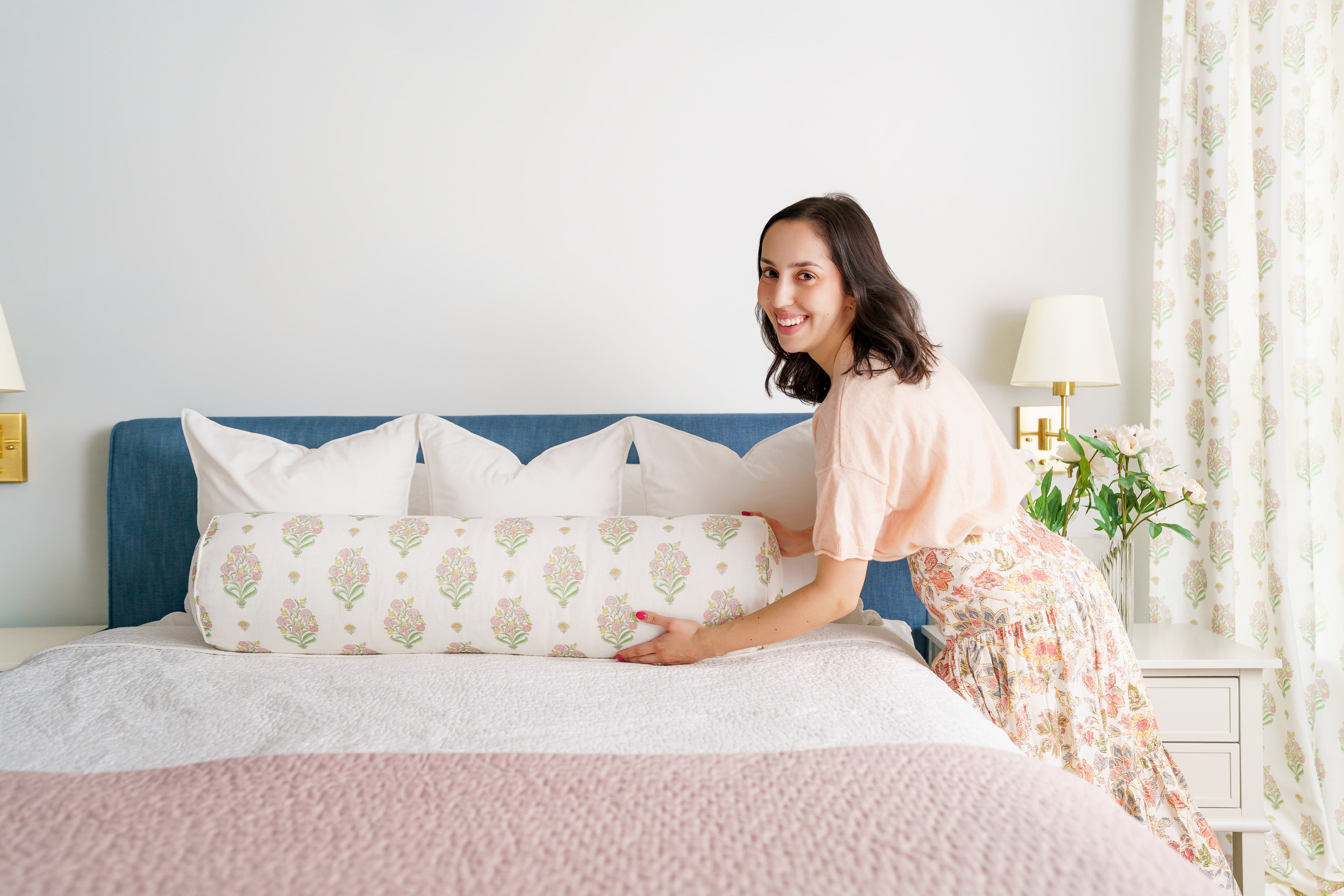 Woman arranging pillows on a bed in a bedroom setting