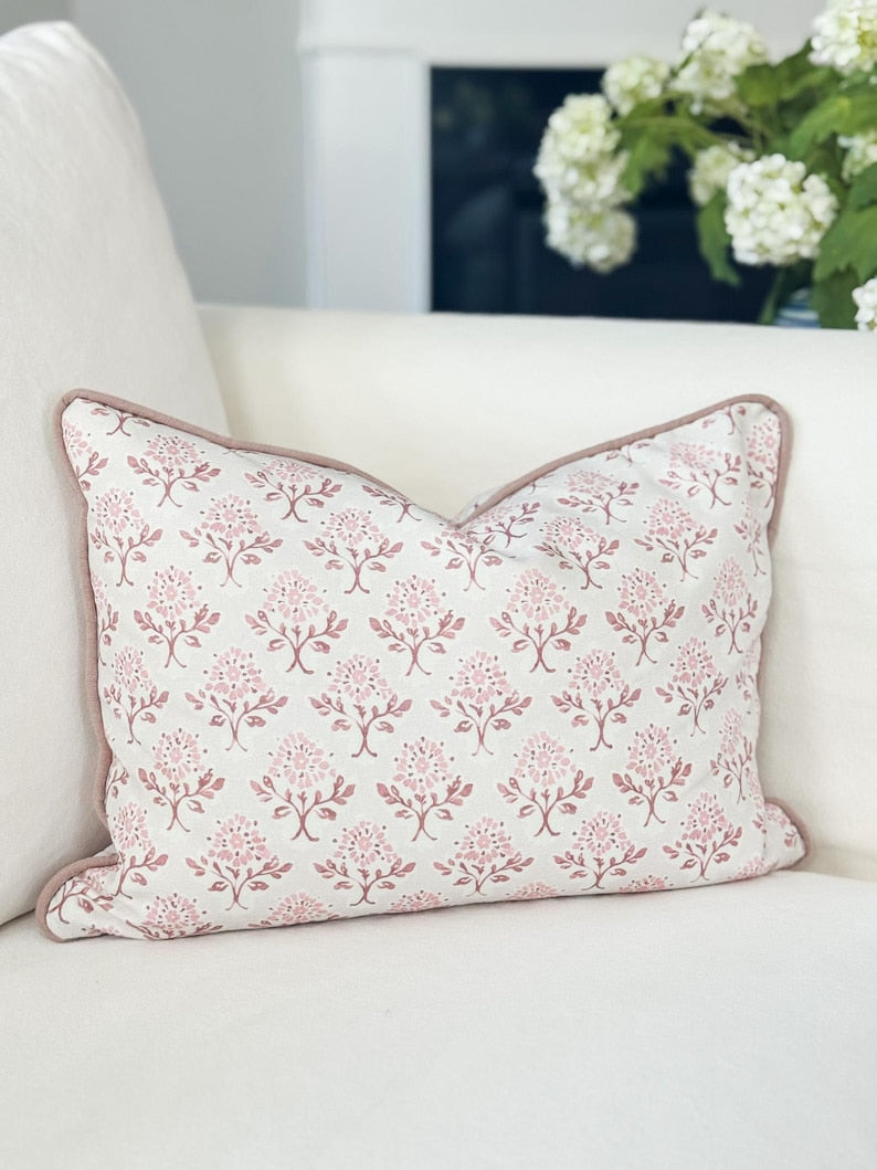Decorative pillow with floral pattern on a white sofa with a blurred plant in the background