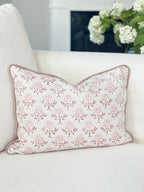 Decorative pillow with floral pattern on a white sofa with a blurred plant in the background